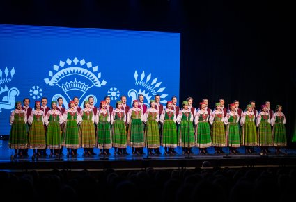 Chór w kostiumach kurpiowskich na scenie podczas koncertu