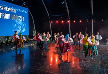 Pary Artystów w kostiumach opoczyńskich na scenie podczas wykonywania choreografii tanecznej