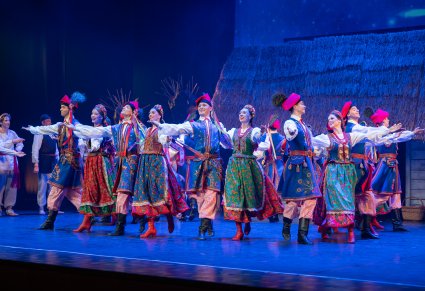 Na scenie grupa Artystów w kostiumach krakowskich w trakcie wykonywania choreografii tanecznej