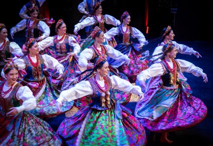 Tancerki w kostiumach krakowskich w obrotach na scenie