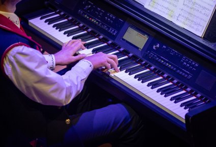 Zbliżenie na instrument akompaniatora, ubranego w kostium wilanowski