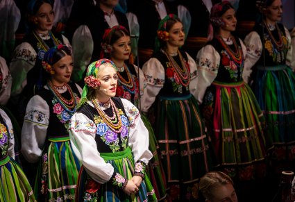 Zbliżenie na solistkę chóru podczas koncertu z widocznych chórem w tle