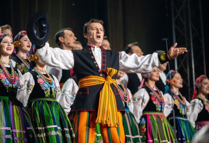 Solista wraz z chórem w kostiumach łowickich podczas śpiewu
