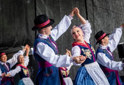 Pary Artystów w kostiumach kaszubskich na scenie wykonujący choreografię taneczną