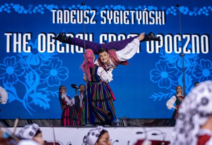 Na pierwszym planie  para Artystów w kostiumach opoczyńskich wykonująca spektakularną choreografię taneczną