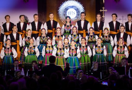 Na pierwszym planie dwie solistki w trakcie śpiewu, w tle Artyści Chóru w kostiumach łowickich, niżej część Orkiestry w kostiumach wilanowskich