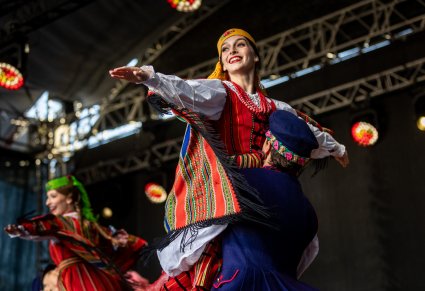 Na pierwszym planie para Artystów w kostiumach sieradzkich, Artysta podnosi do góry Artystkę