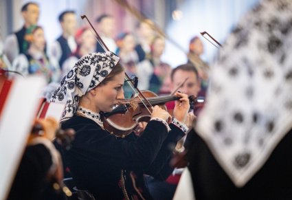 Zbliżenie na Artystkę Orkiestry w kostiumie wilanowskim grającą na instrumencie smyczkowym