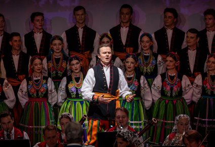 Zbliżenie na solistę chóru podczas koncertu z widocznych chórem w tle