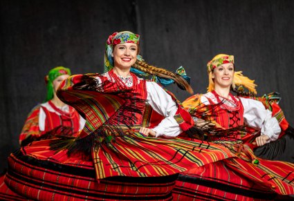 Trzy Artystki w kostiumach sieradzkich na scenie w tańcu spódnica kobiecego kostiumu faluje miękko, ukazując bogactwo barw