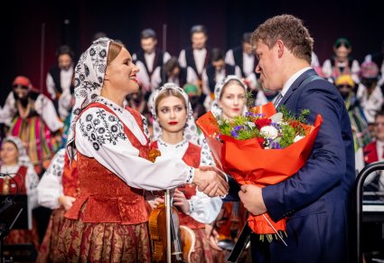 Zbliżenie na dyrygenta z kwiatami i artystkę orkiestry po skończonym koncercie