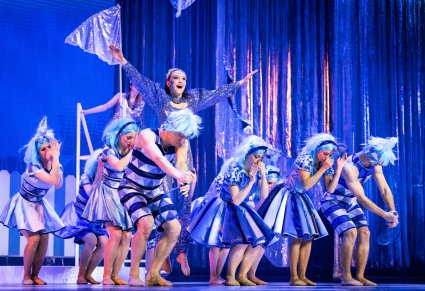 Wspólna scena postaci trójkątów wraz z postacią gwiazdy. Gwiazda ma na sobie srebrny, świecący kostium, trójkąty niebieskie kostiumy