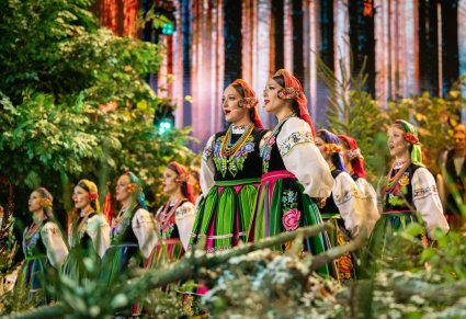 Solistki chóru podczas wykonywania "Dwóch Serduszek", w tle częśc chóru, wszyscy w kostiumach łowickich
