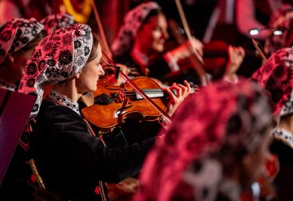 Zbliżenie na artystkę orkiestry grającą na instrumencie smyczkowym
