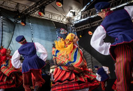 Dwie pary Artystów w kostiumach sieradzkich podczas wykonywania choreografii tanecznej na scenie