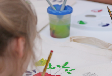 Uczestniczka warsztatów "Lasowiackie serca" maluje farbą na torebce