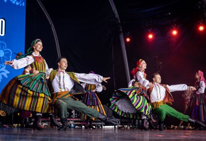 Pary Artystów na scenie w kostiumach opoczyńskich wykonujący choreografię taneczną na scenie