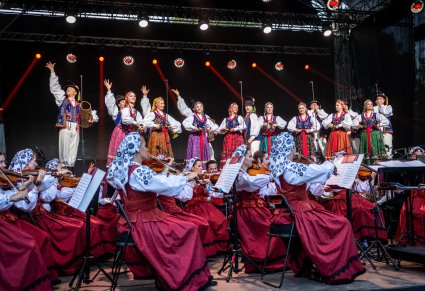 Artyści na scenie w kostiumach limanowskich z widoczną orkiestrą