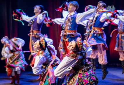 Zbliżenie na tancerki w kostiumach krakowskich z widocznymi tancerzami w tle