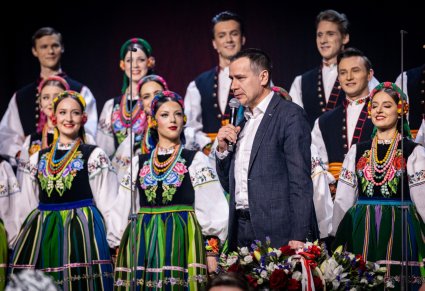 Zbliżenie na Burmistrza podczas przemówienia, w tle widoczny chór w kostiumach łowickich