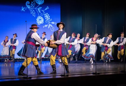 Na scenie Artyści w kostiumach kaszubskich, na pierwszym planie dwóch Artystów grających na burczybasie