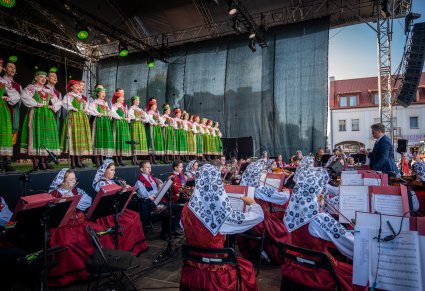 Widok na orkiestrę a na scenie chór w rzędzie w kostiumach kurpiowskich