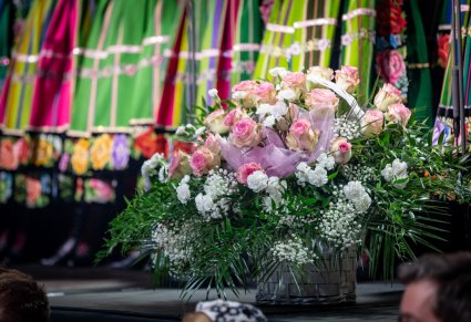 Zbliżenie na kosz kwiatów, w tle widoczne spódnice łowickie
