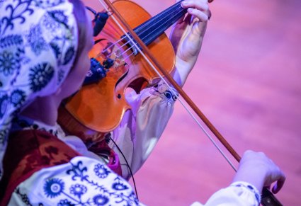 Zbliżenie na Muzyczkę w kostiumie wilanowskim grającej na instrumencie smyczkowym