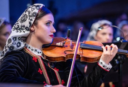 Zbliżenie na Muzyczkę w kostiumie wilanowskich grającą na instrumencie smyczkowym