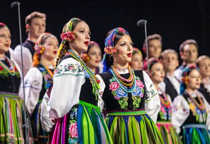 Solistki chóru w kostiumach łowickich,  w tle częśc chóru także w kostiumach łowickich