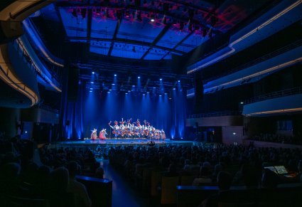 Widok na scenę z z występującymi tancerzami w kostiumach krakowskich