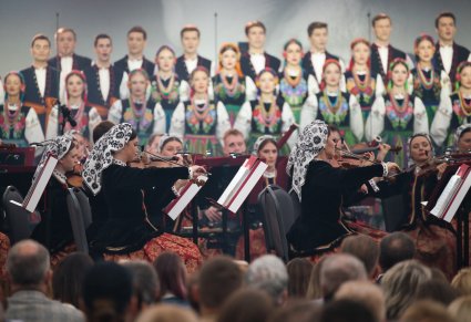 Widok na część chóru w kostiumach łowickich i część orkiestry w kostiumach wilanowskich, z perspektywy publiczności