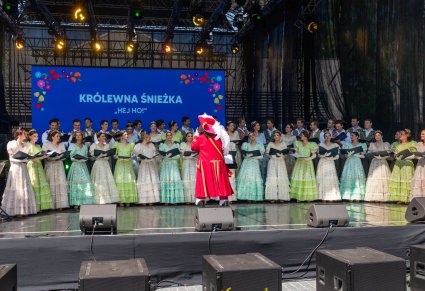 Na scenie głównej Artyści Chóru w stylizowanych kostiumach z XIX wieku, przed nimi Dyrygent w kostiumie Kapitana Hack'a