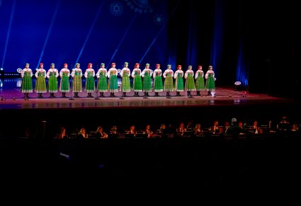 Na scenie Artystki chóru w kostiumach kurpiowskich podczas śpiewu, niżej widoczna część orkiestry