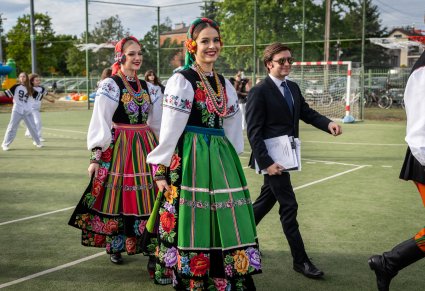 Zbliżenie na dwie Artystki chóru w kostiumach łowickich i Akompaniator w czarnym garniturze