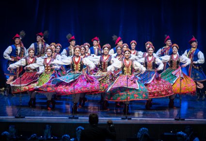 Tancerki w kostiumach krakowskich w obrotach na scenie