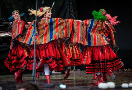 Artystki na scenie w kostiumach sieradzkich wykonujące choreografię taneczną