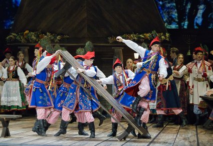 Grupa Artystów w kostiumach krakowskich w choreografii tanecznej wykorzystującej ławę