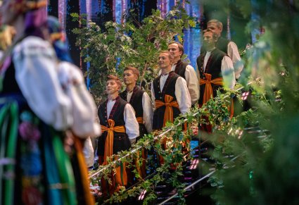 Zbliżenie na kilku chórzystów w kostiumach łowickich podczas występu na scenie festiwalu