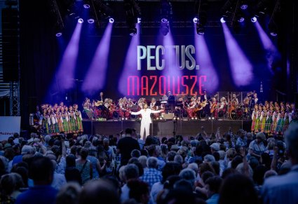 Na środku sceny wokalista zespołu Pectus, po bokach sceny Artyści chóru w kostiumach łowickich, w tle Orkiestra w kostiumach wilanowskich