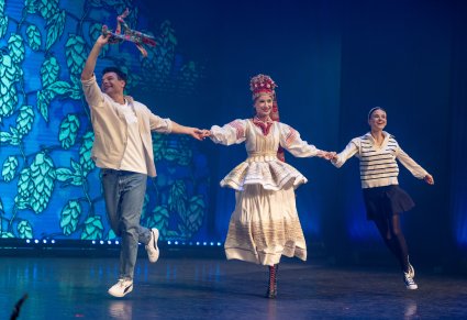 Zbliżenie na artystkę w ślubnym kostiumie krzczonowskim z aktorami na scenie