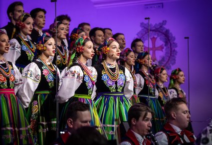Zbliżenie na Solistki Chóru w kostiumach łowickich, w tle część Artystów Chóru