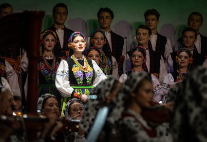 Zbliżenie na solistkę chóru podczas koncertu z widocznych chórem w tle