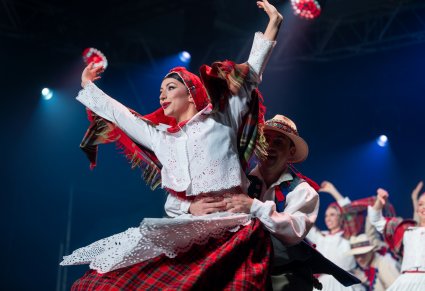 Na pierwszym planie para Artystów w kostiumach łańcuckich w trakcie wykonywania choreografii tanecznej