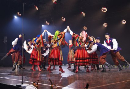 Na scenie grupa Artystów w kostiumach sieradzkich w trakcie wykonywania choreografii tanecznej