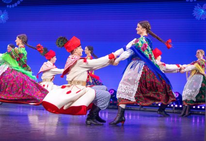 Na pierwszym planie para Artystów w kostiumach krakowskich w tle reszta część par w trakcie wykonywania choreografii tanecznej