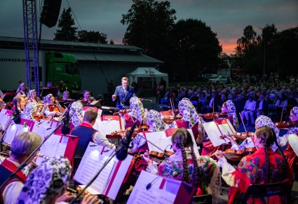 Widok z perspektywy sceny na orkiestrę w kostiumach wilanowskich i podhalańskich oraz dyrygenta,
