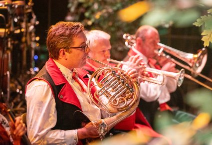 Zbliżenie na muzyków orkiestry w kostiumach wilanowskich, grających na instrumentach dętych