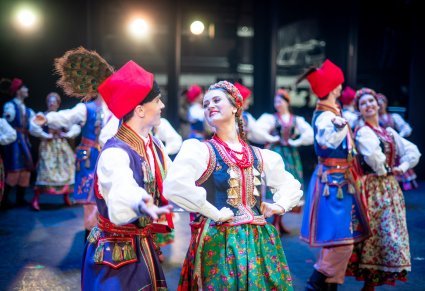 Zbliżenie na parę Artystów zespołu "Mazowsze" w kostiumach krakowskich w trakcie wykonywania choreografii tanecznej