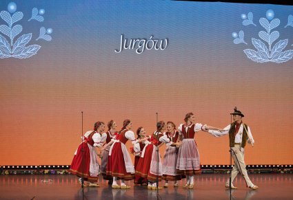 Grupa Artystów w kostiumach jurgowskich w trakcie wykonywania choreografii tanecznej